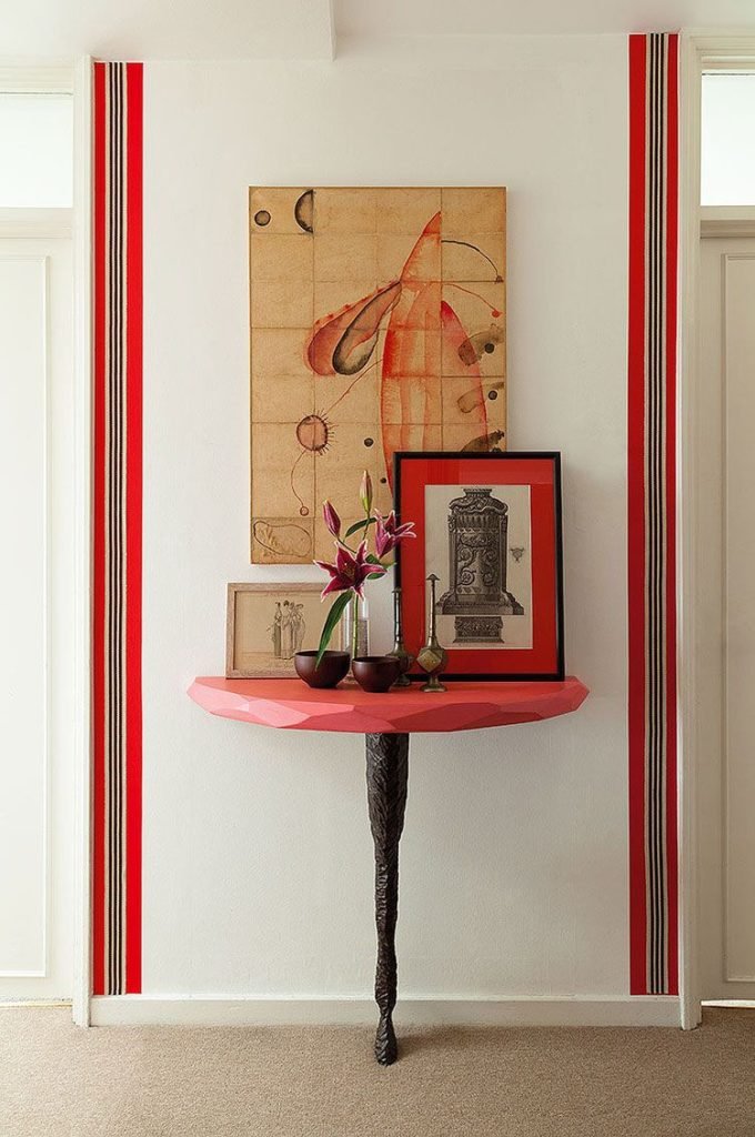 A hallway table with accessories in red with a border for framing the entrance hall